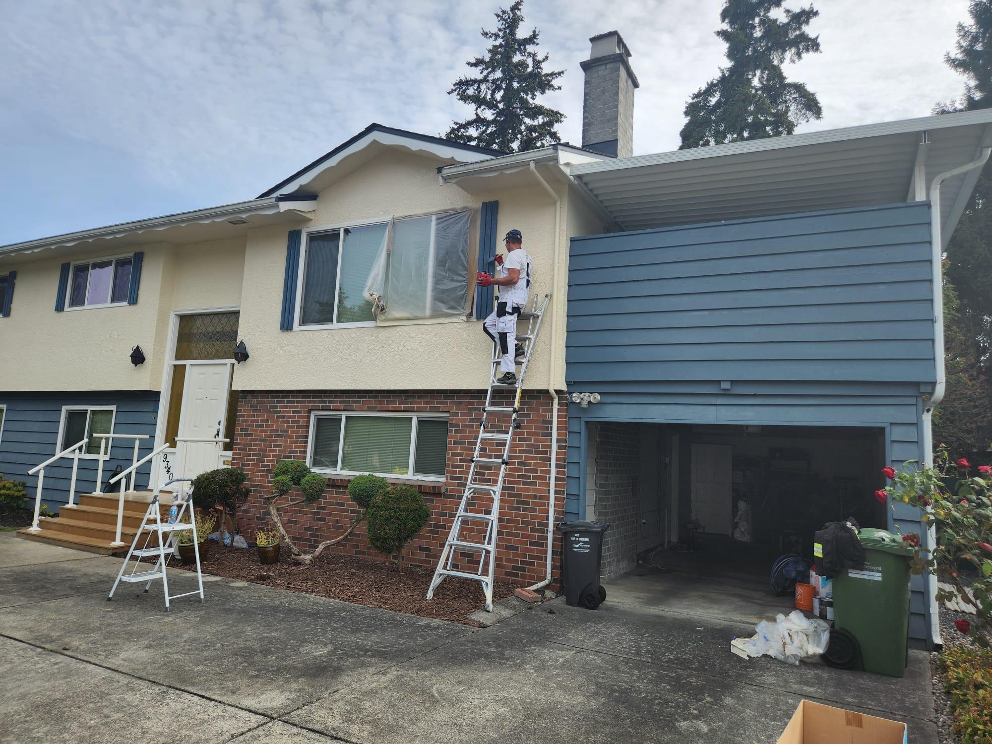 Professional painter applying exterior paint to a residential house
