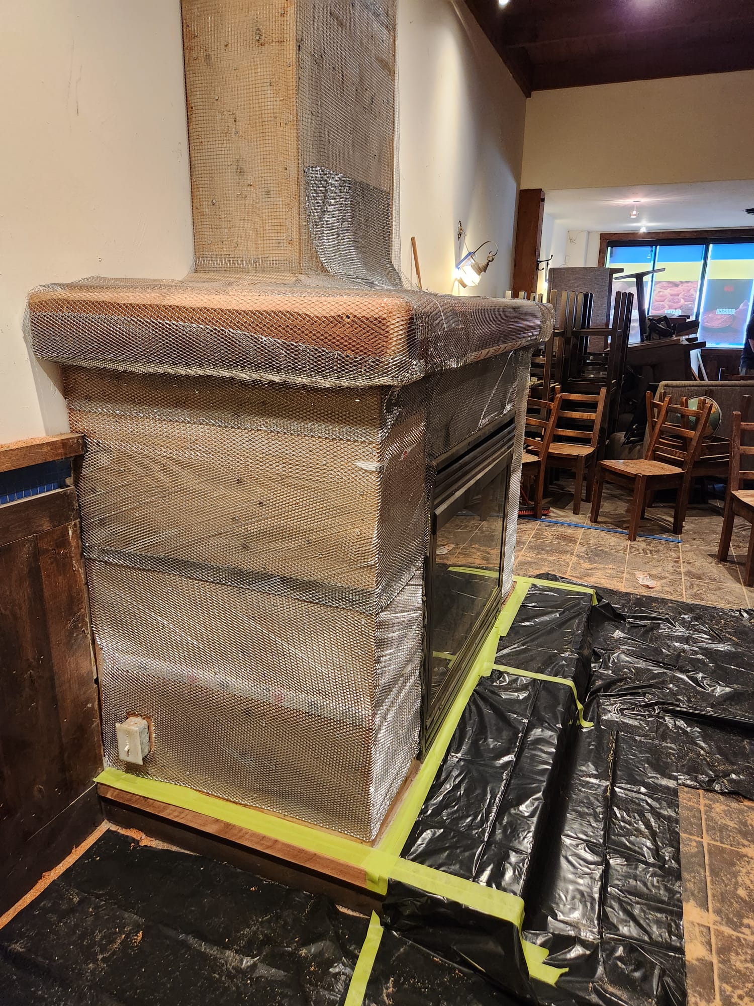 Metal mesh being installed over the custom fireplace structure